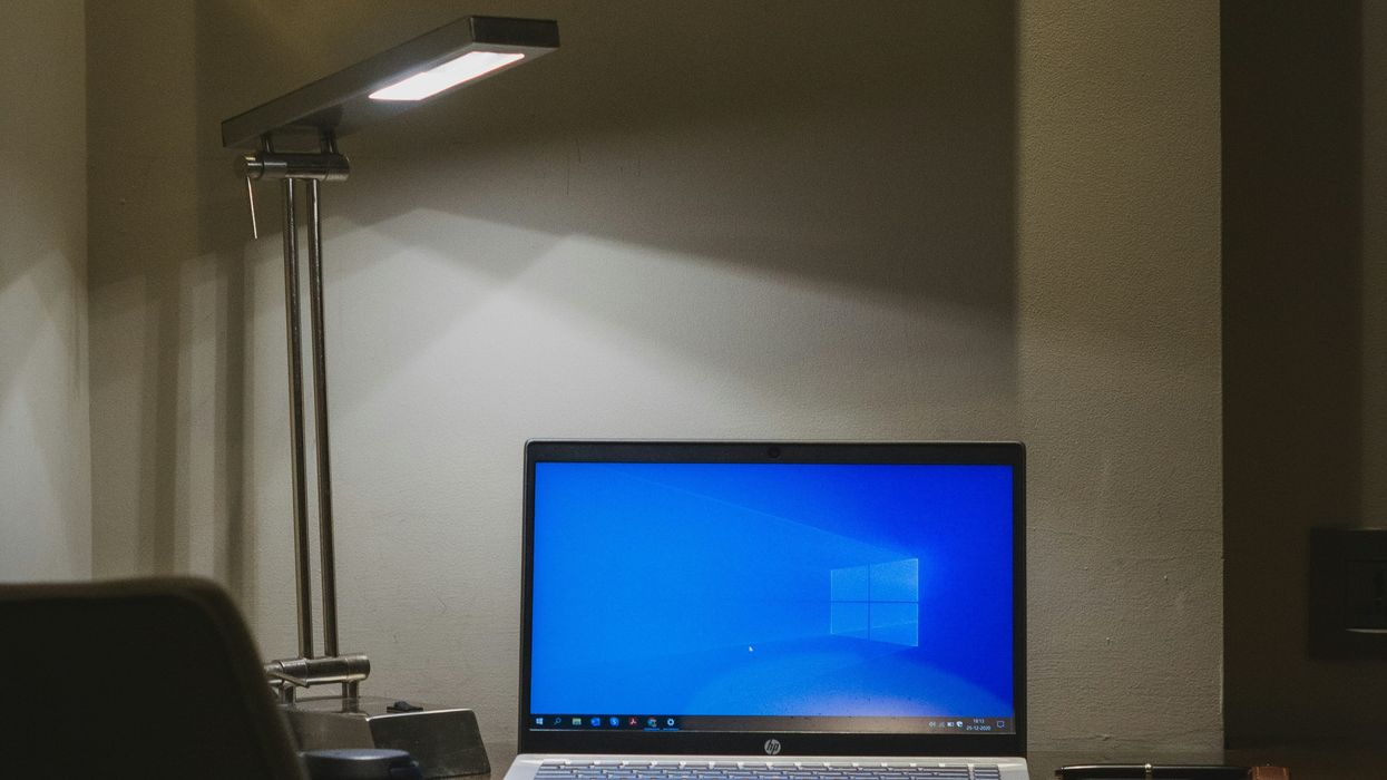 windows 10 laptop sat on a desk lit by a lamp