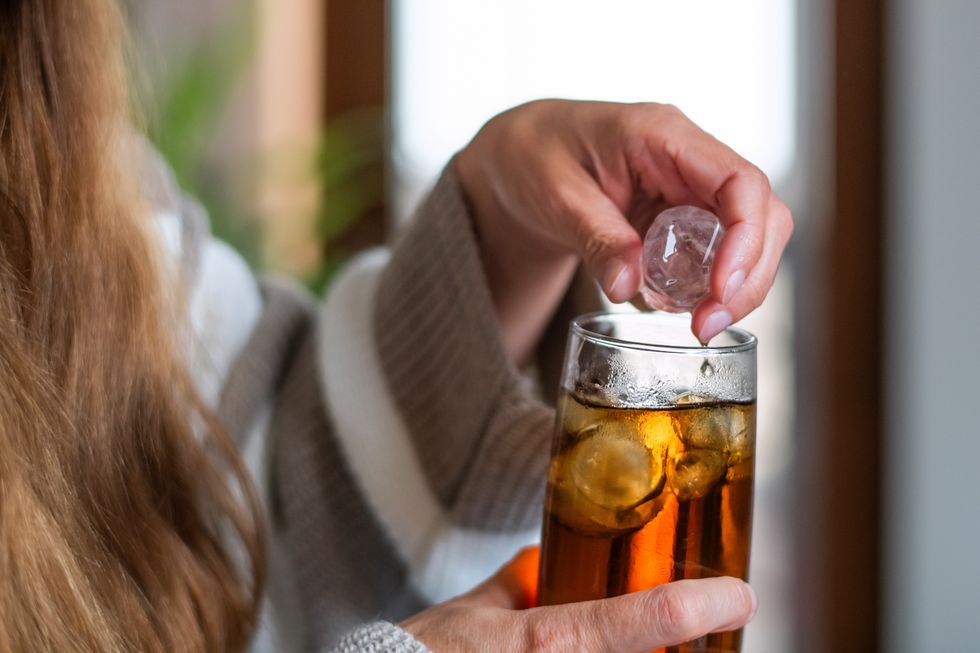 woman adding ice to soft drink