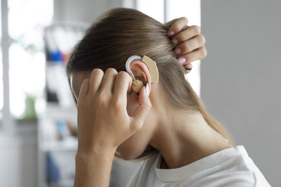 WOMAN ADJUSTING HEARING AIDS