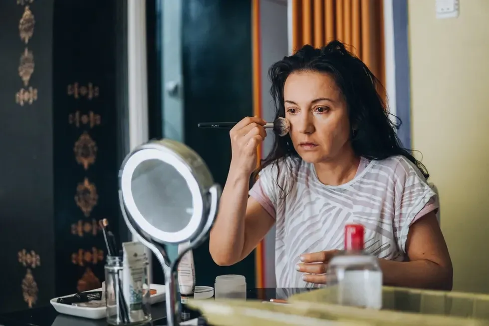 Woman applying bronzer to her cheeks