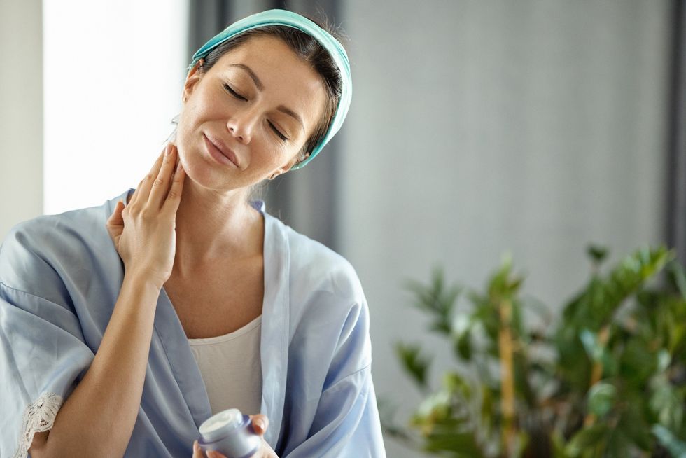 Woman applying skin care cream to her neck