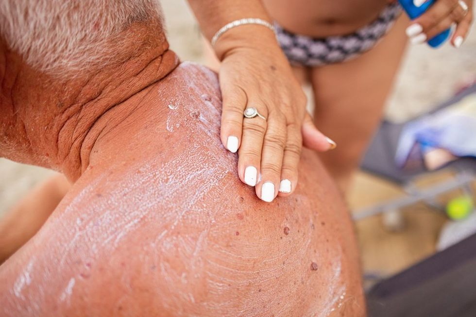 woman applying sun cream to man's back