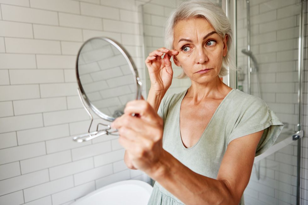 WOMAN CHECKING FACE IN MIRROR