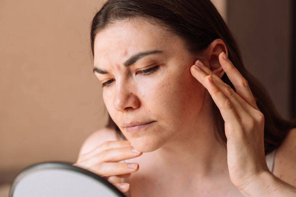 woman checking pores in mirror