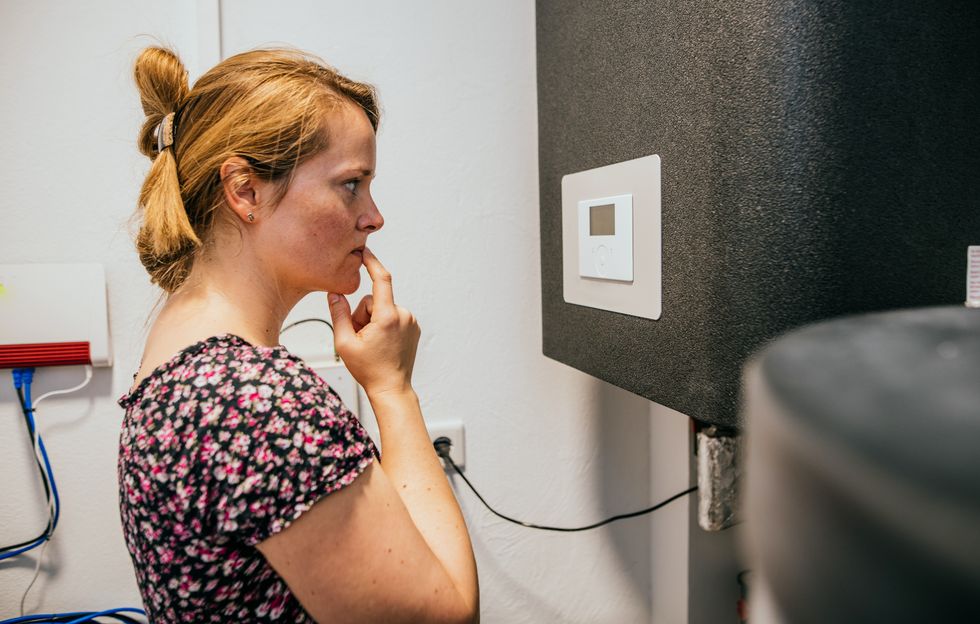 Woman controlling the heat pump unit at home