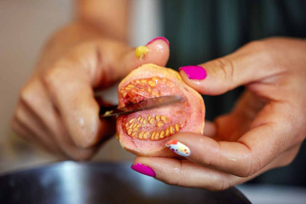 WOMAN CUTTING GUAVA FRUIT