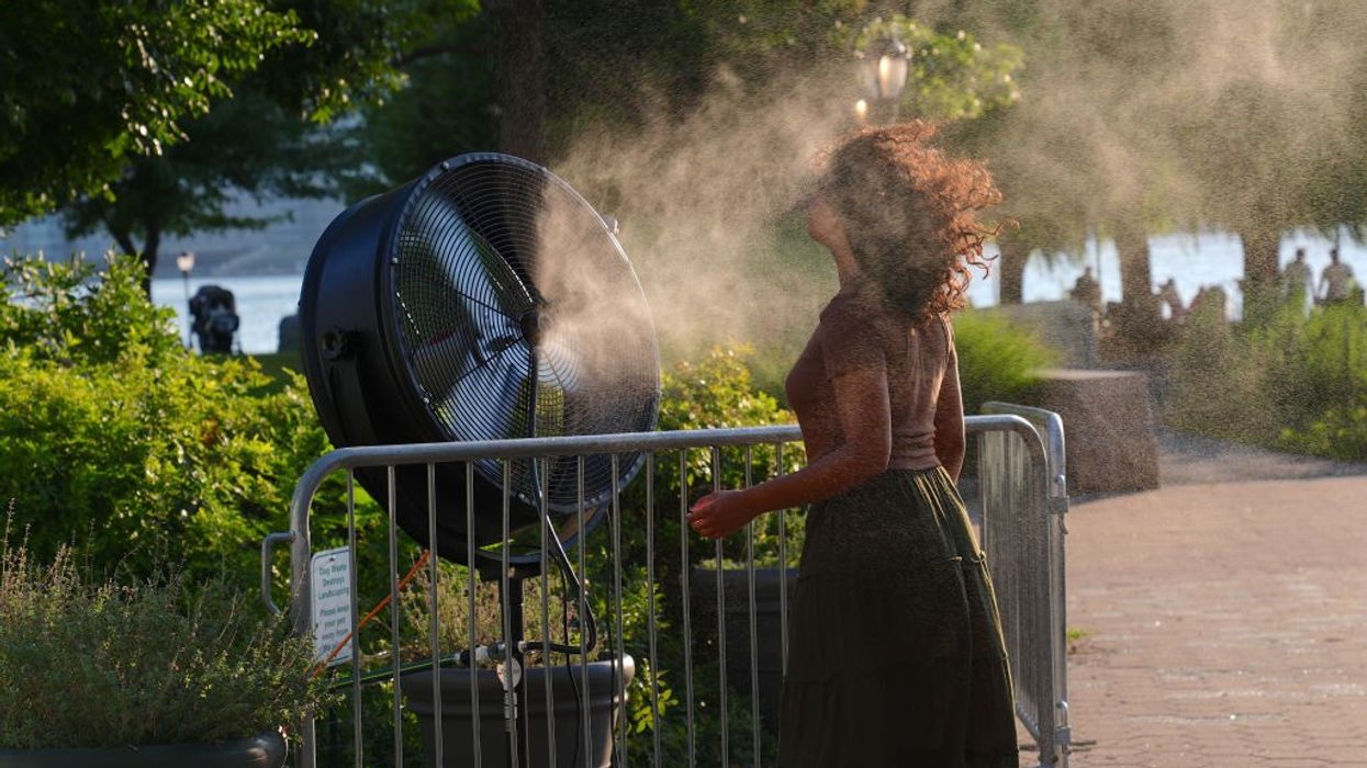 Woman dealing with heatwave by having a fan blow water on her