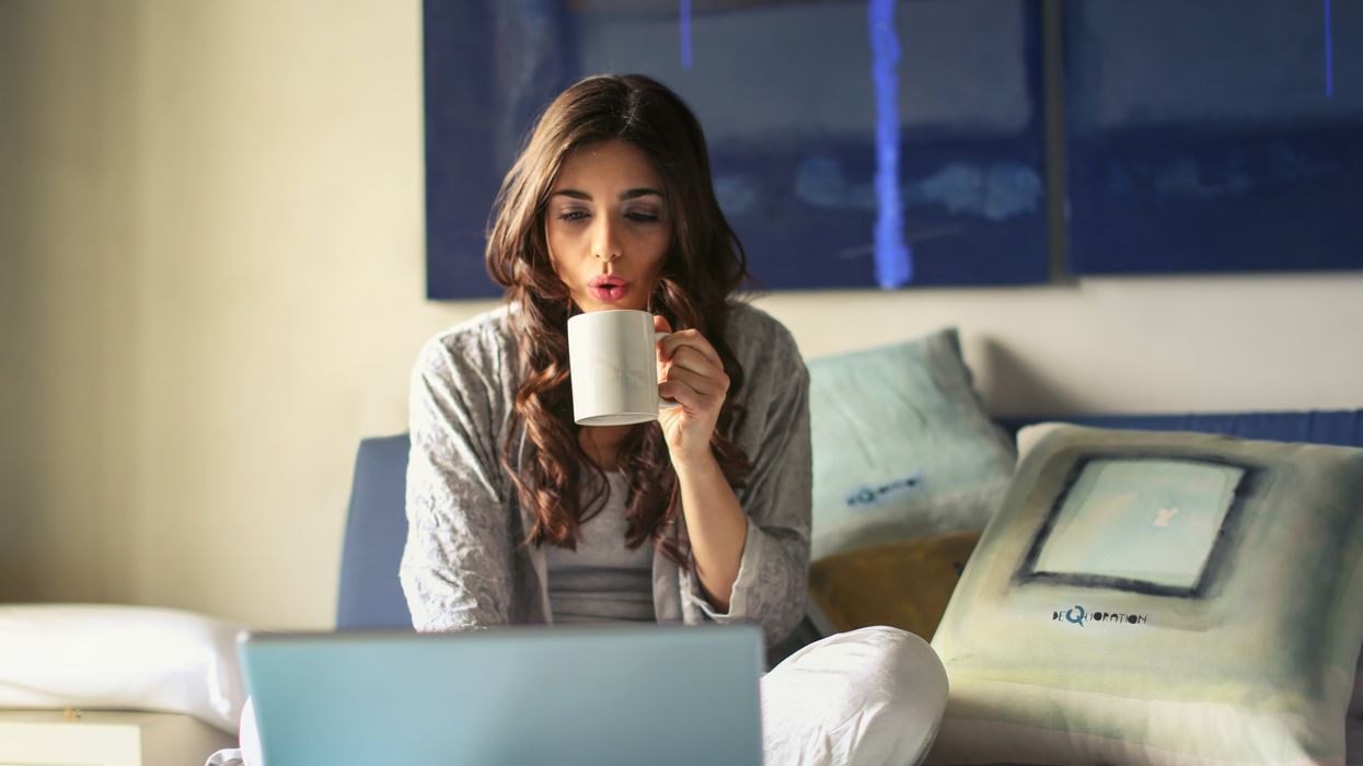 Woman drinking coffee while working on bed
