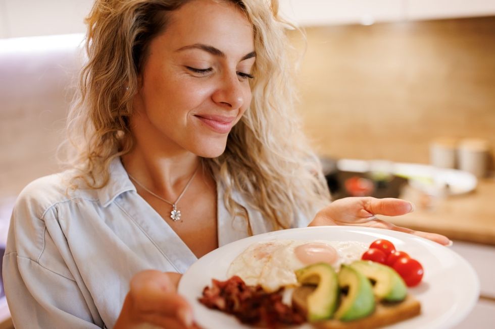 Woman eating eggs, avocado and toast