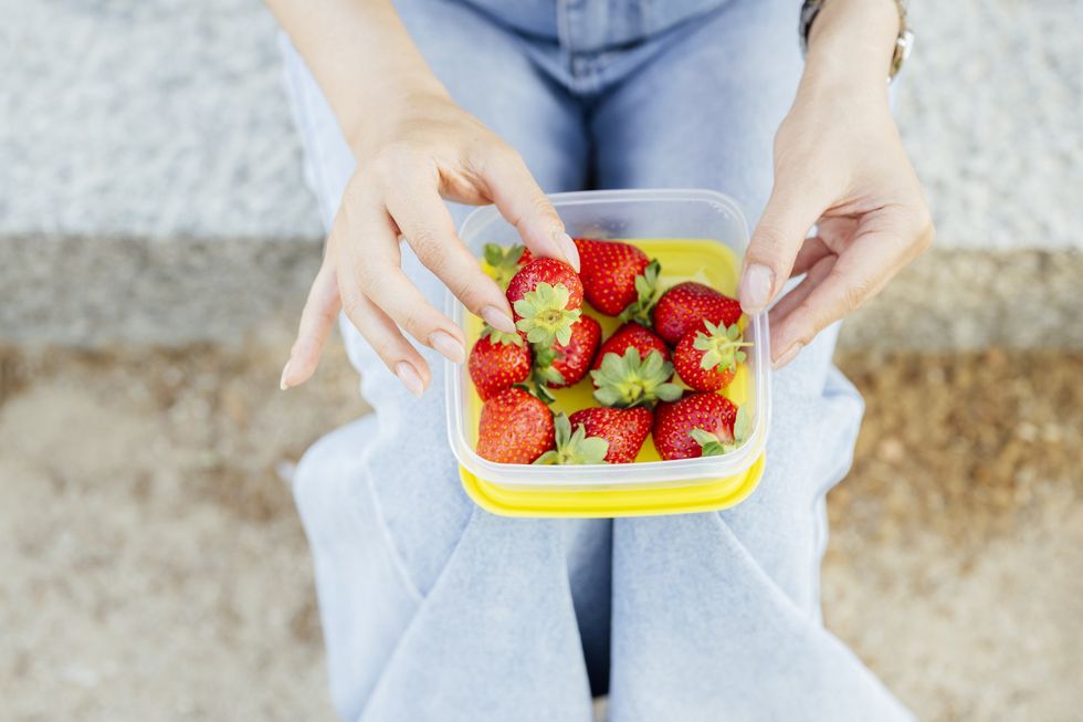 Woman eating from a container of strawberries