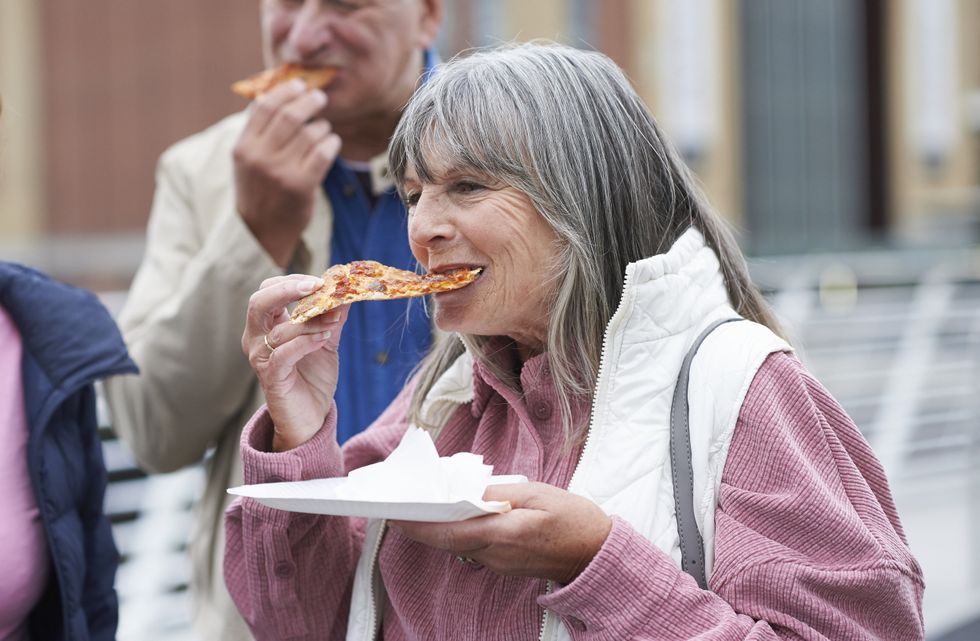 WOMAN EATING SLICE OF PIZZA