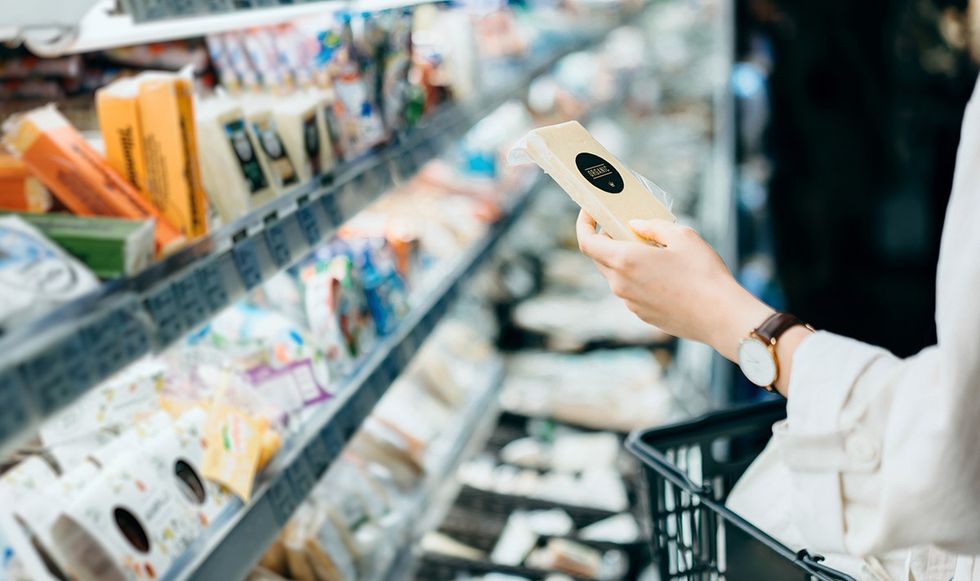 Woman examining cheese in shop aisle