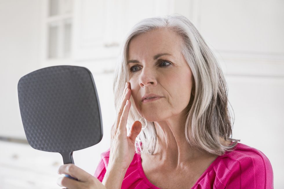 Woman examining face in the mirror