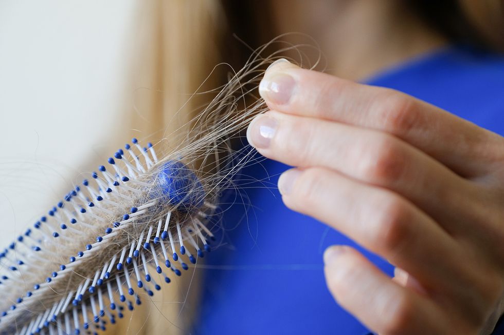 Woman examining hair brush for shedding