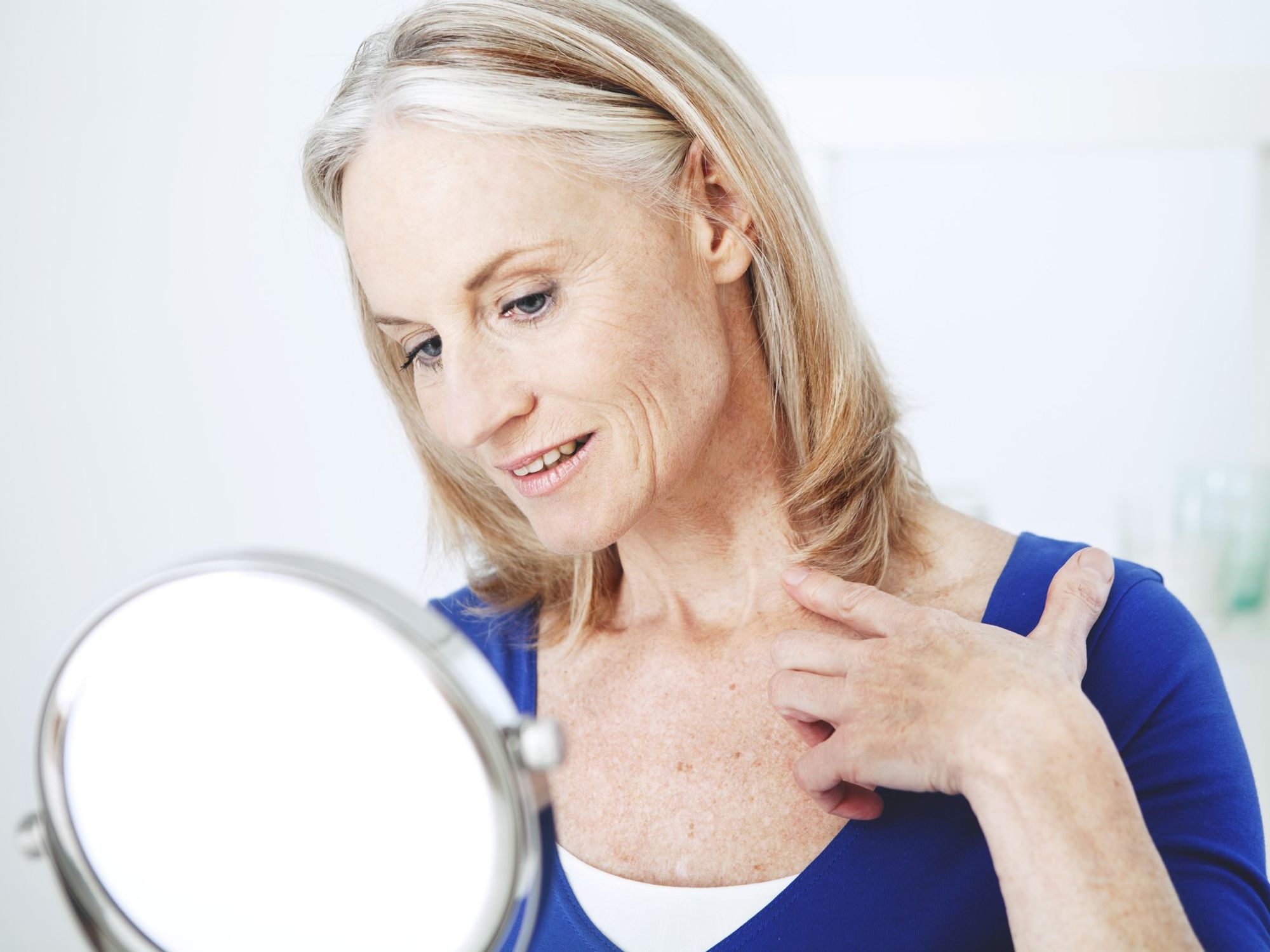 Woman examining her neck in mirror
