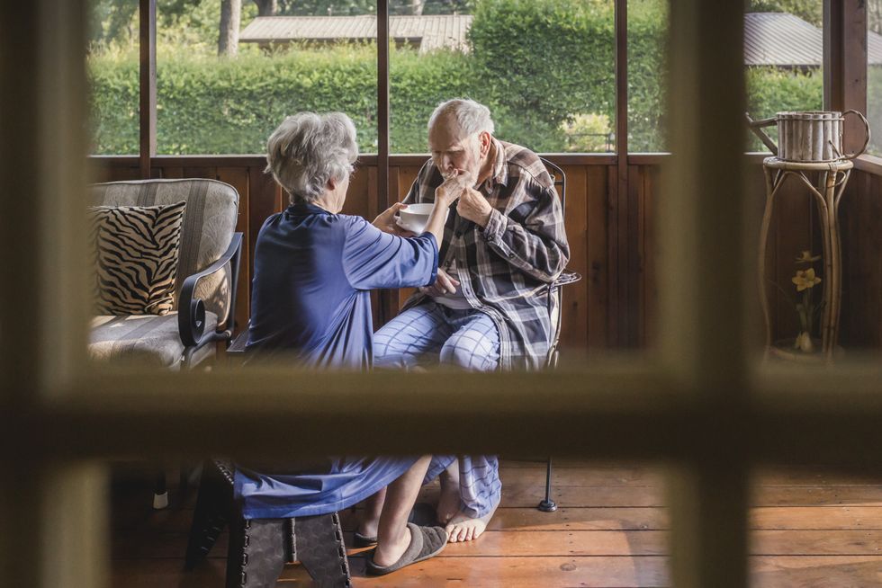 Woman feeding man with Parkinson's disease