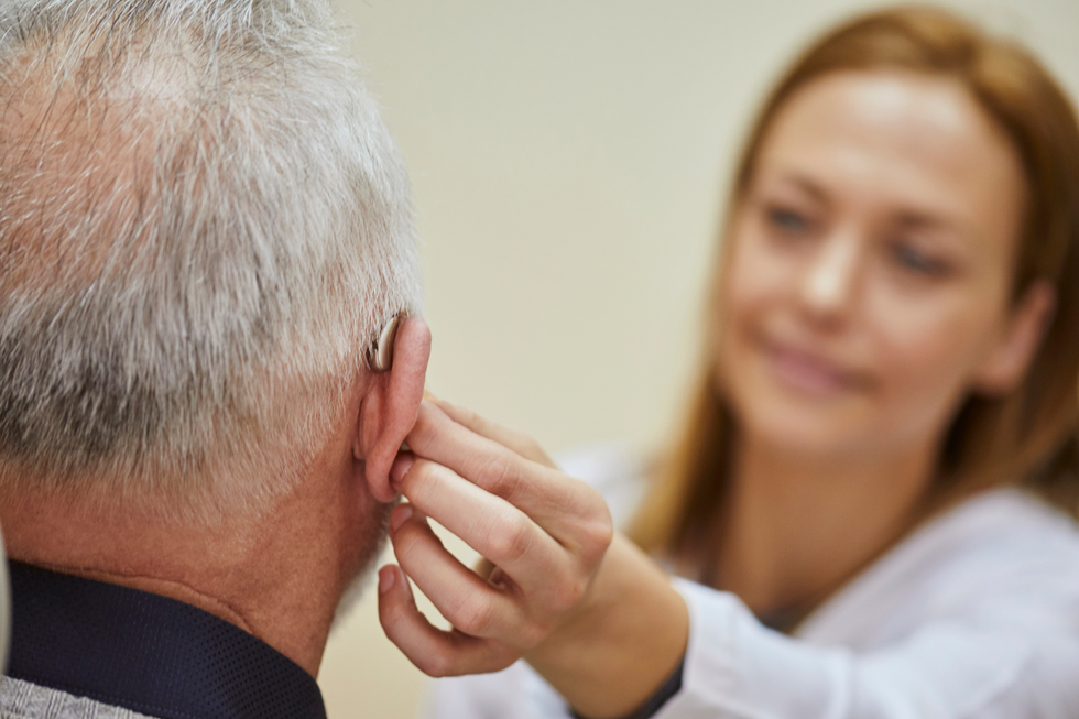 Woman helping man with his hearing aid