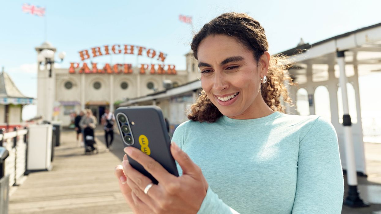woman holding ee smartphone outside of Brighton pier