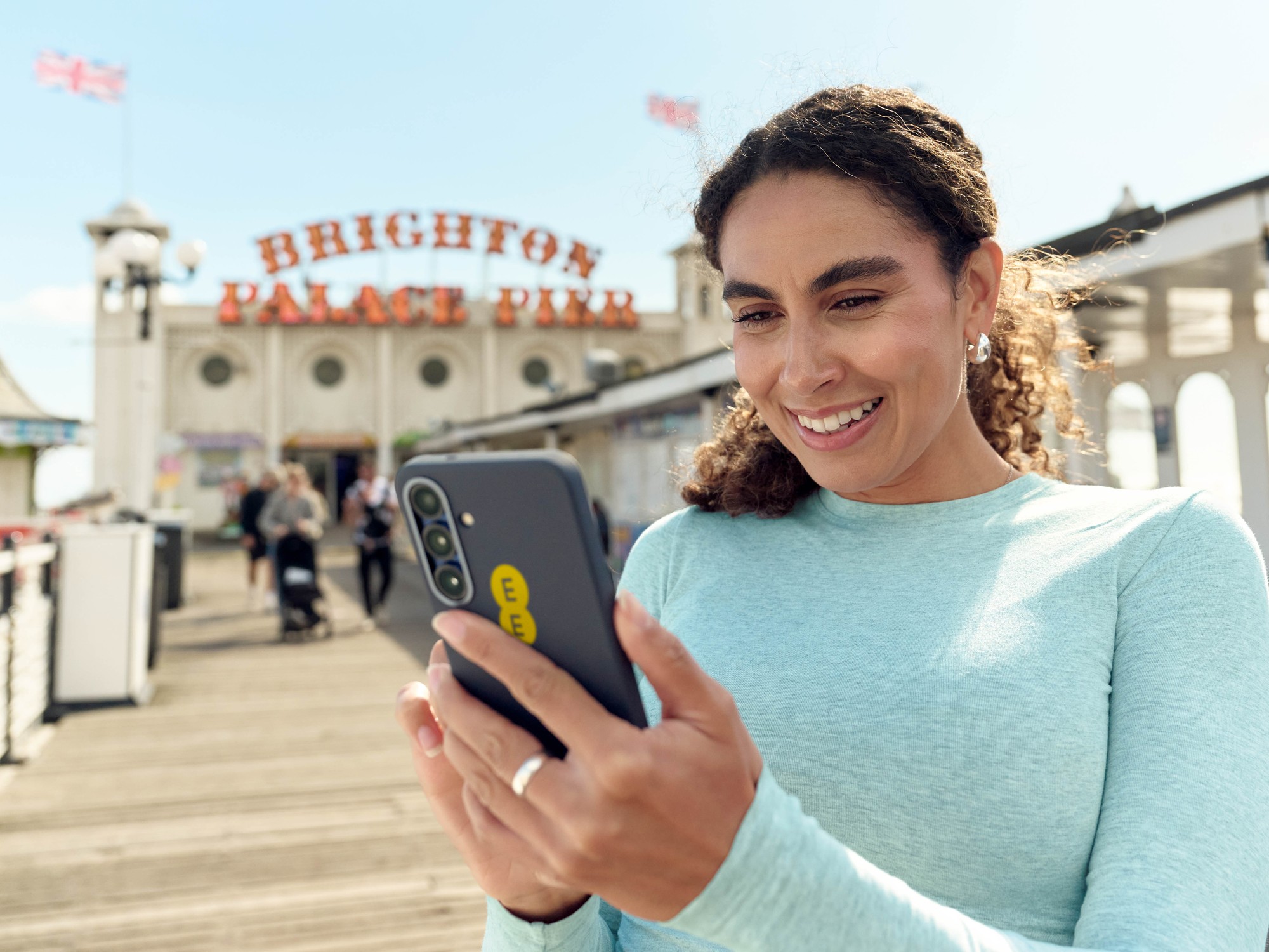 woman holding ee smartphone outside of Brighton pier