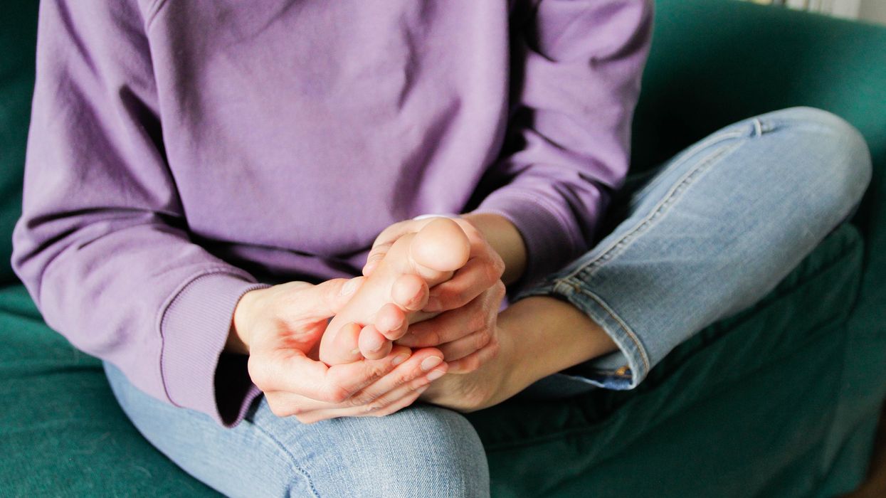 Woman holding her foot on the sofa