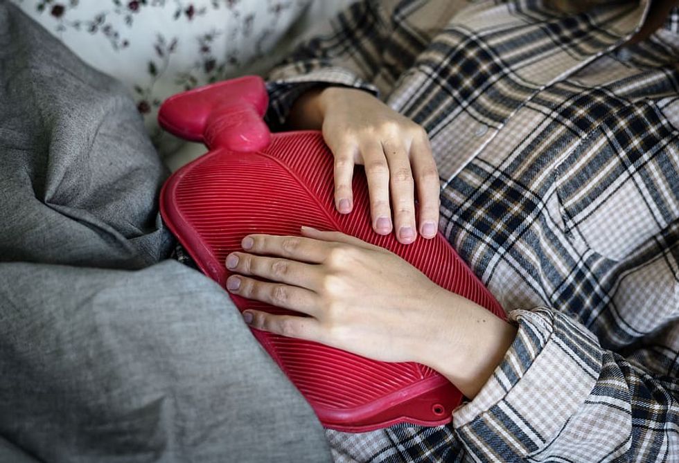 Woman holding hot water bottle to her stomach