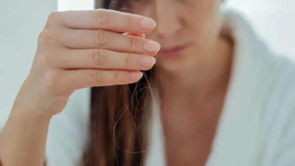 Woman holding strands of hair that have fallen out