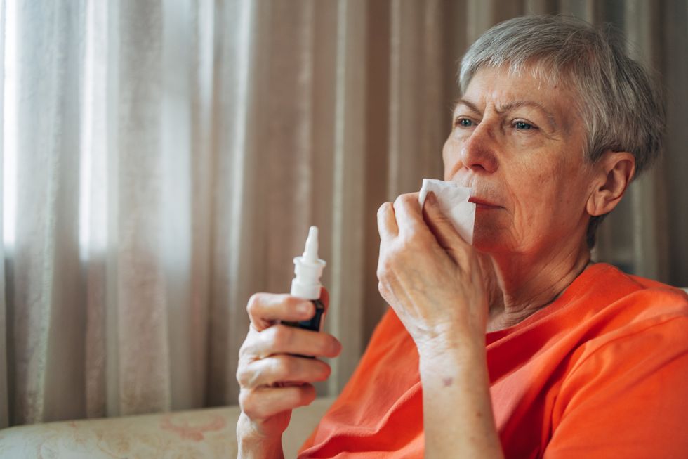 WOMAN HOLDING TISSUE TO NOSE