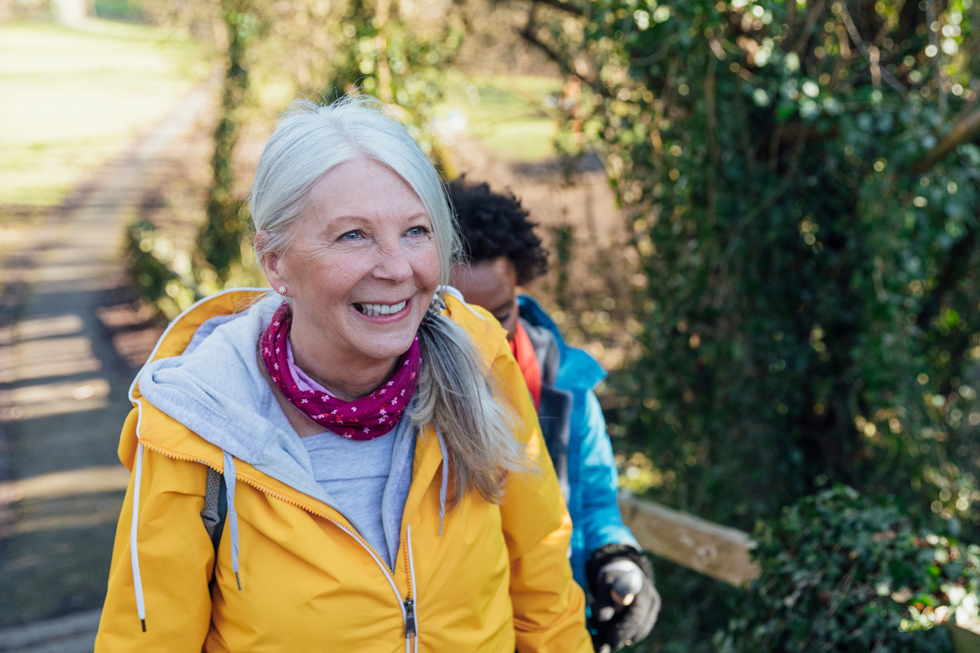 Woman in a yellow jacket going for a walk in nature