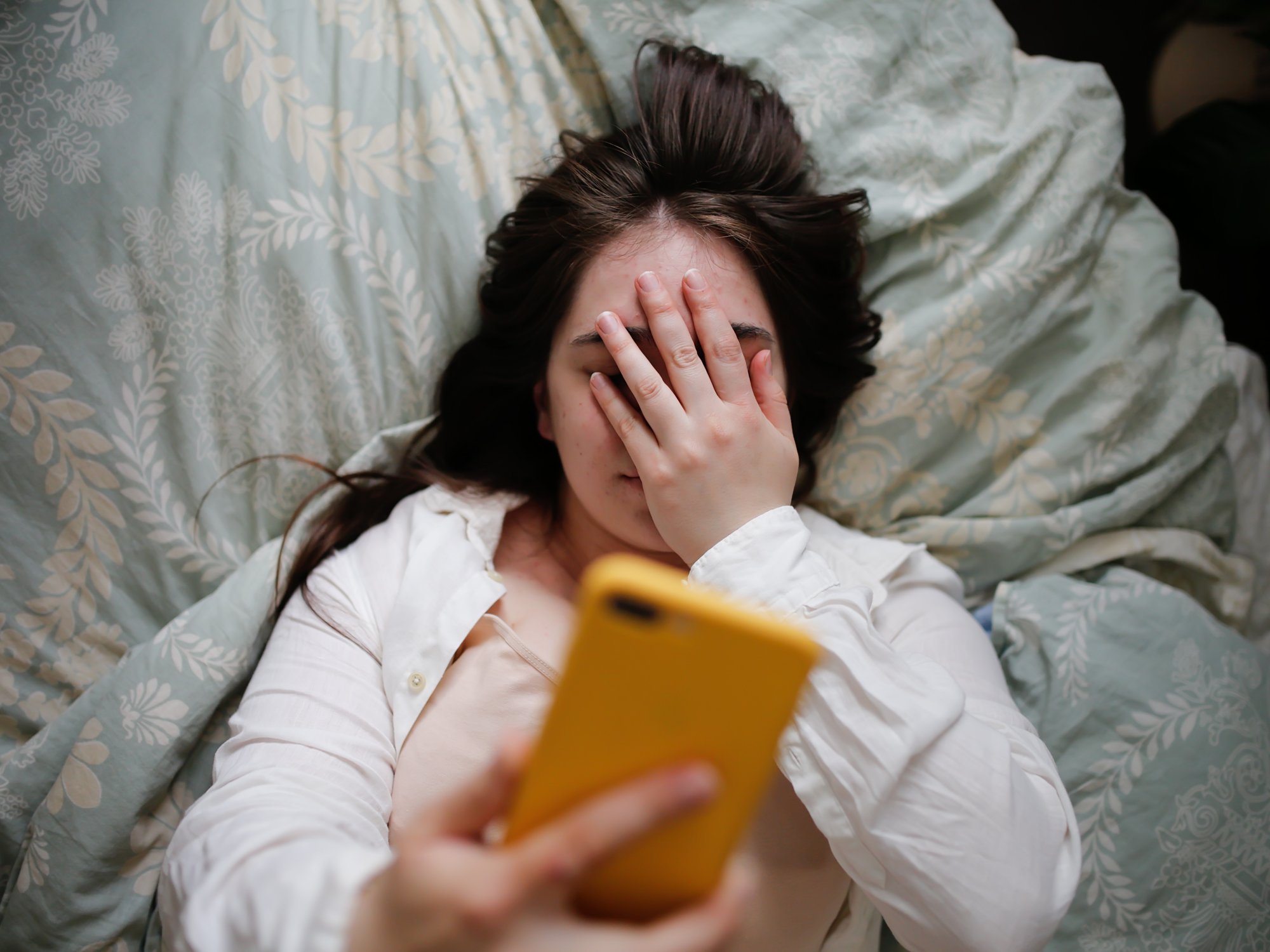 Woman in bed looking at phone
