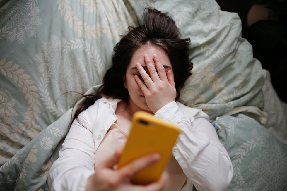 Woman in bed looking at phone