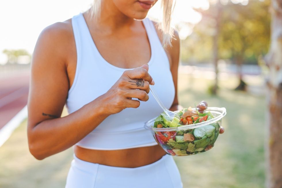 Woman in gym kit eating salad