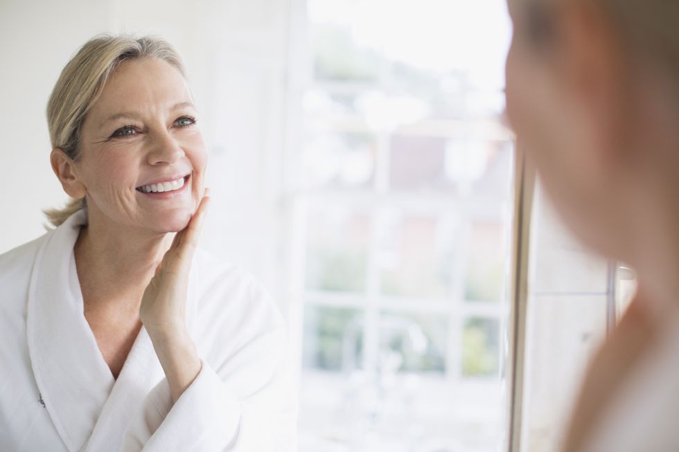 Woman in mirror applying skin care