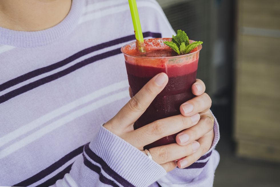 Woman in stripy jumper holding a glass of beetroot juice with a sprig of mint