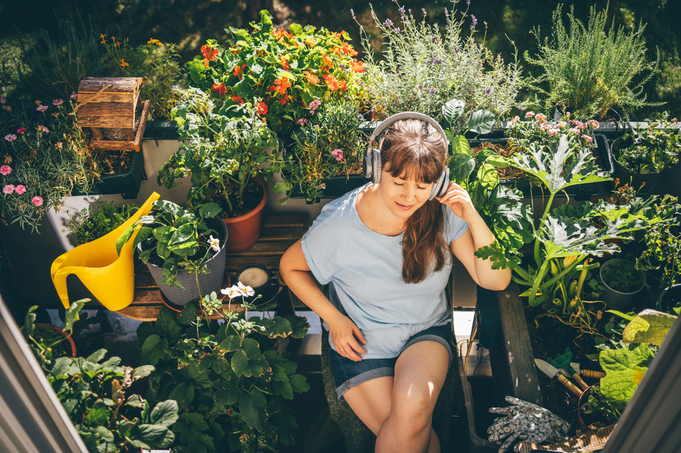 Woman listening to music surrounding by plants in her