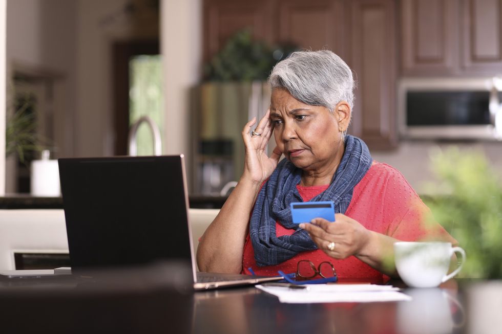 Woman looking at computer while holding credit card