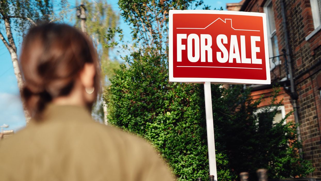 Woman looking at for sale sign outside property