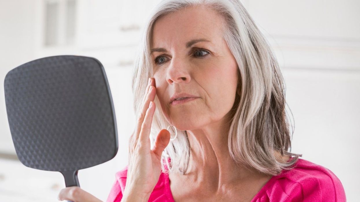 Woman looking at her face in mirror