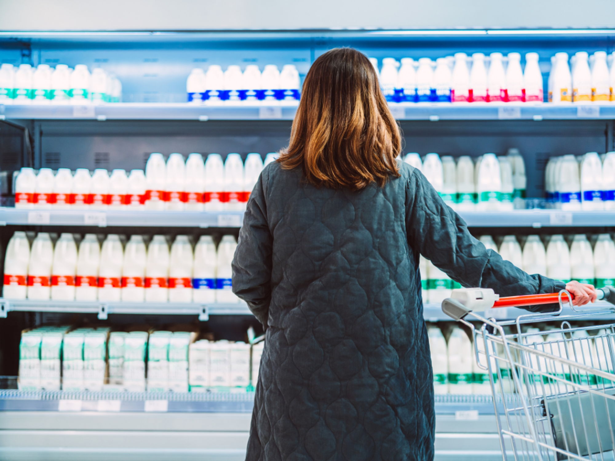Woman looking at milk in a supermarket aisle