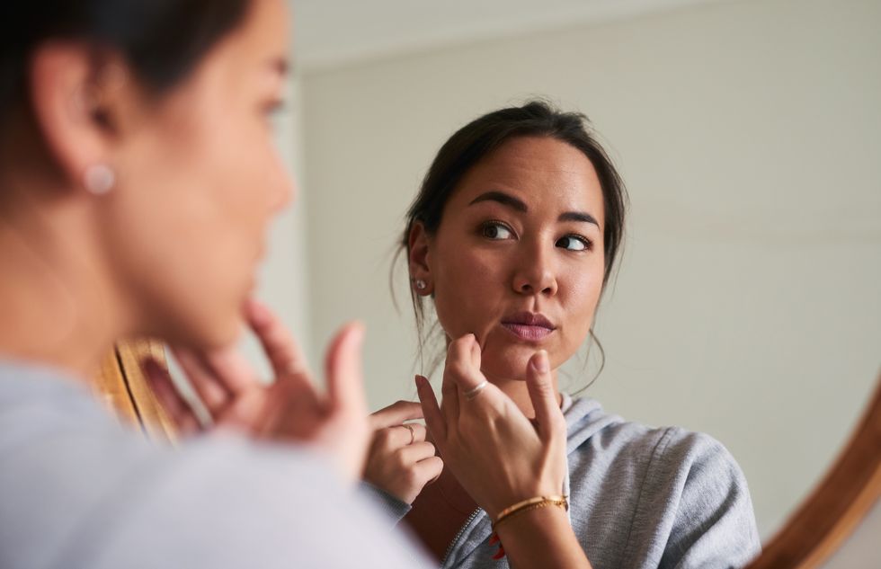 Woman looking at skin in mirror