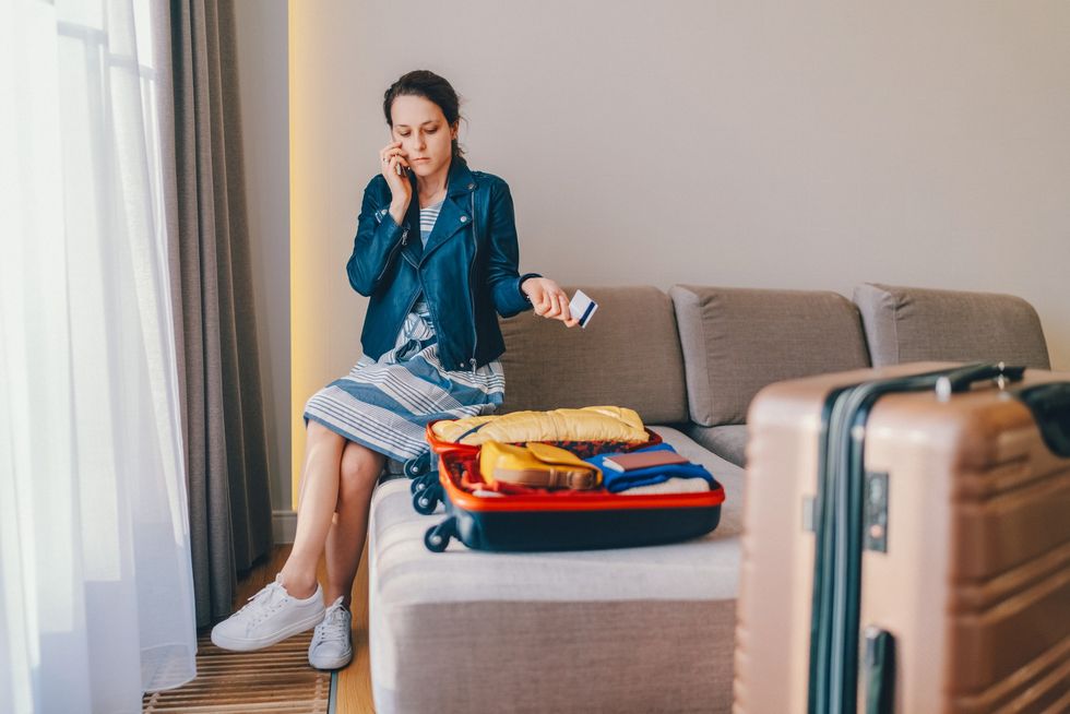 Woman looking at suitcase and dealing with credit card issue over the phone