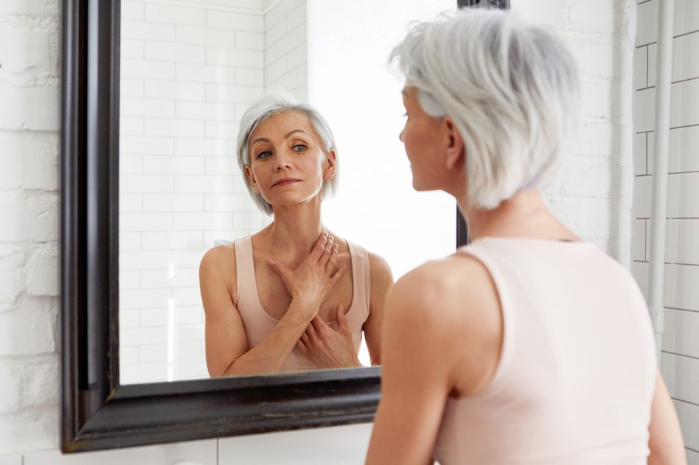 Woman looking in the mirror examining her neck