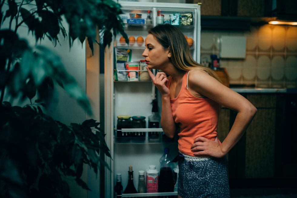 Woman looking into a fridge at night