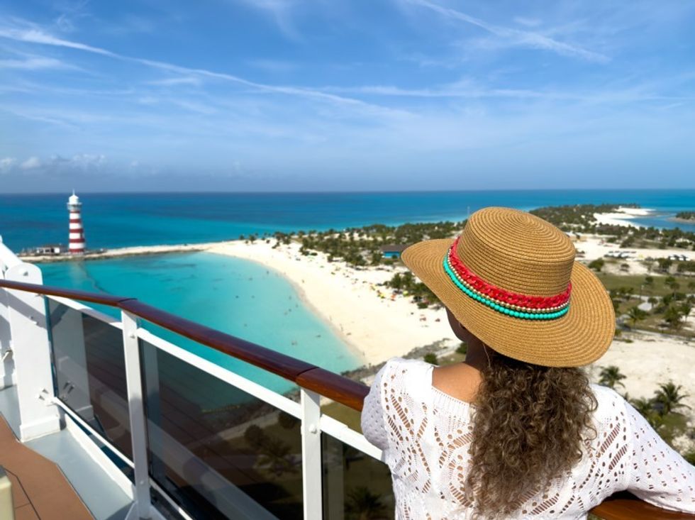 Woman looking off balcony of cruise ship at beach
