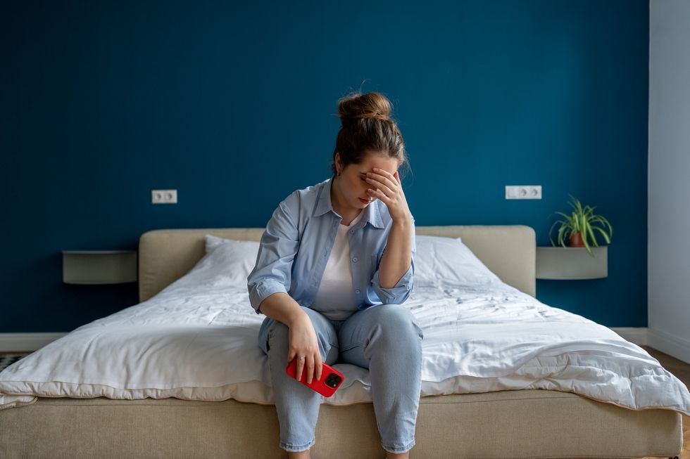 Woman looking upset while sitting on bed