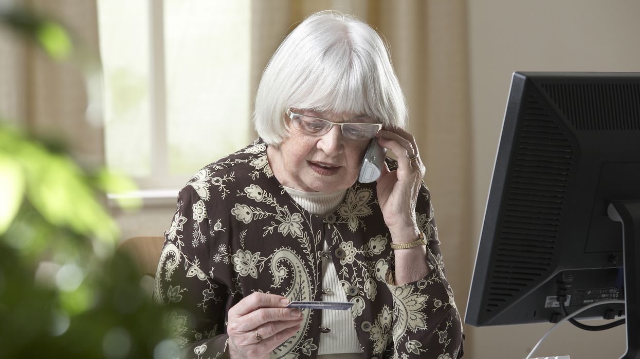 Woman looks at bank card while on phone