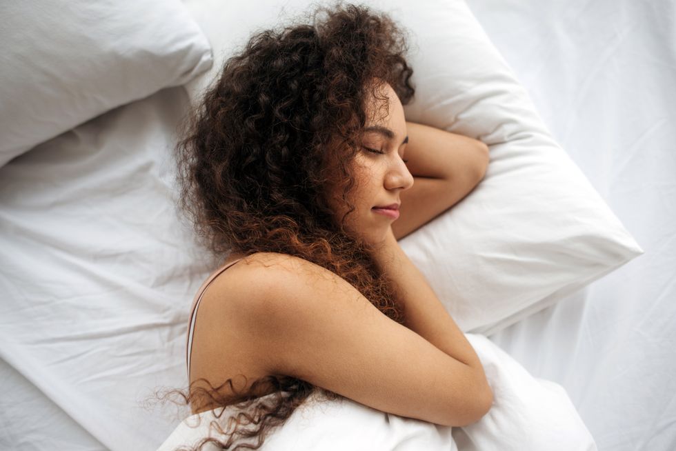 Woman lying in bed with white sheets