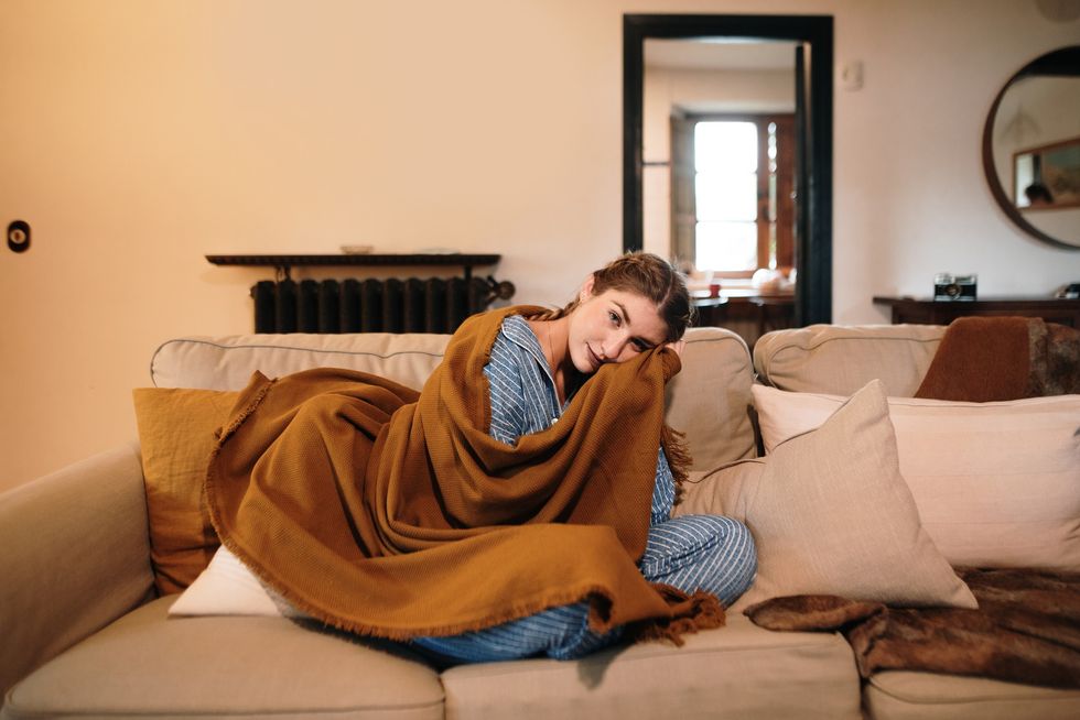 Woman on sofa wrapped in ochre blanket