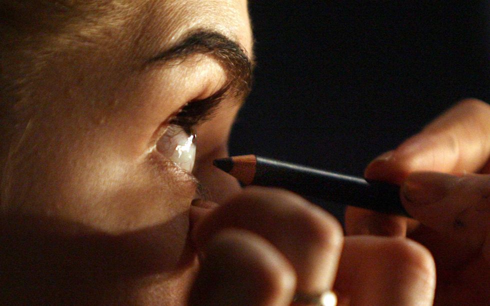 Woman putting on eyeliner