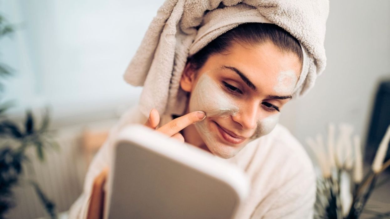 Woman putting on face mask in mirror