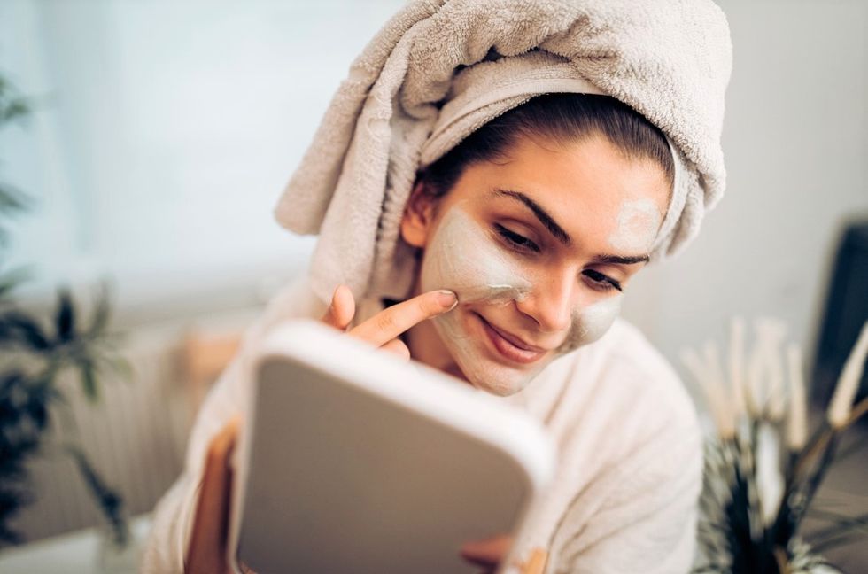 Woman putting on face mask in mirror